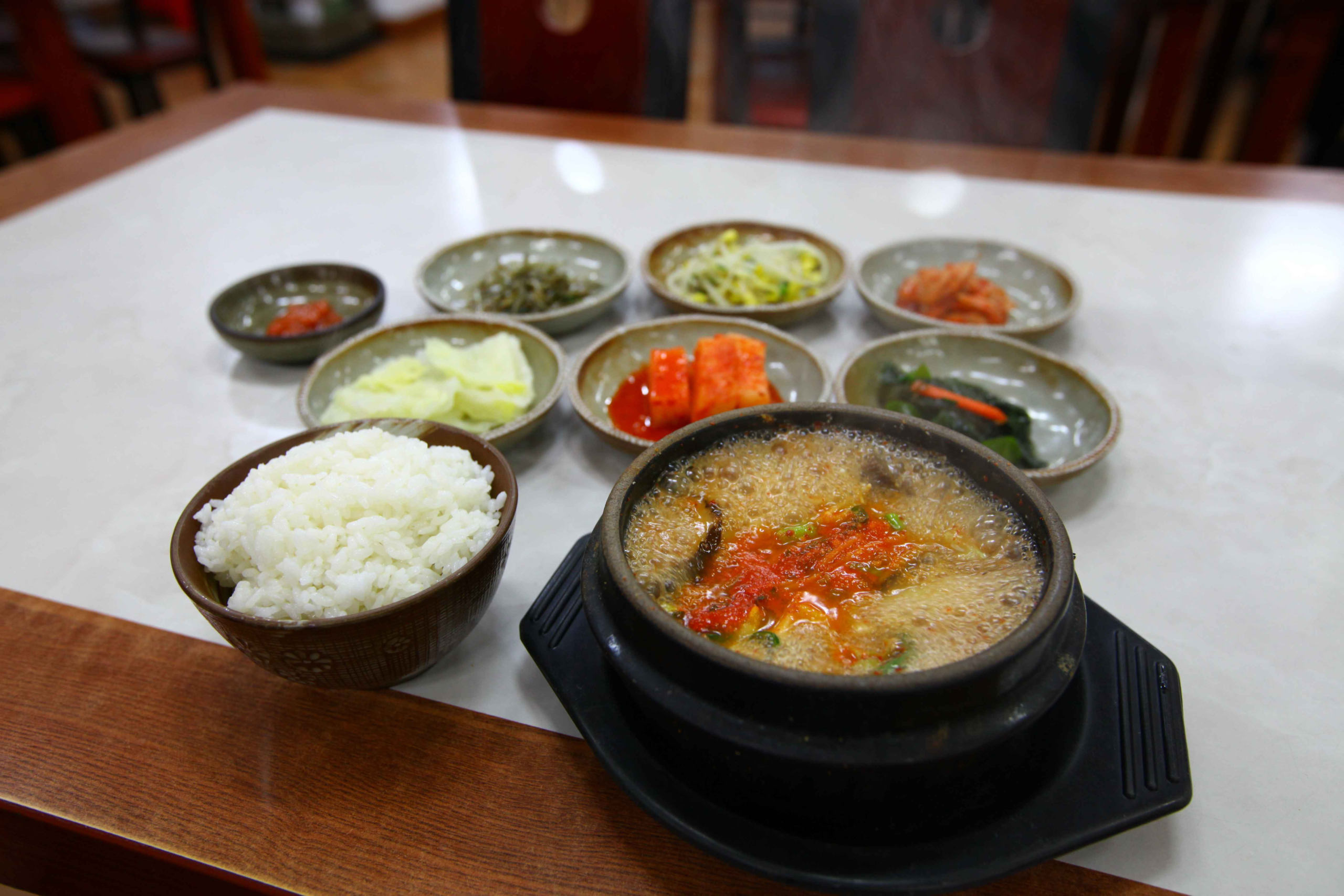 Doenjang jjigae Korean soybean paste stew served in black stone pot with rice and traditional banchan side dishes