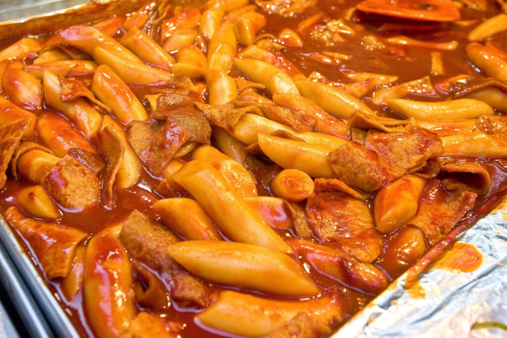 Spicy Korean tteokbokki rice cakes coated in glossy gochujang sauce with fish cakes in a pan