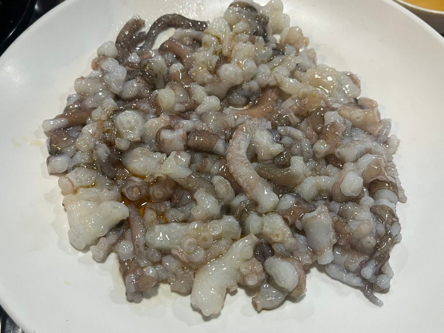 Sannakji octopus tentacles moving on white plate showing fresh texture and suction cups