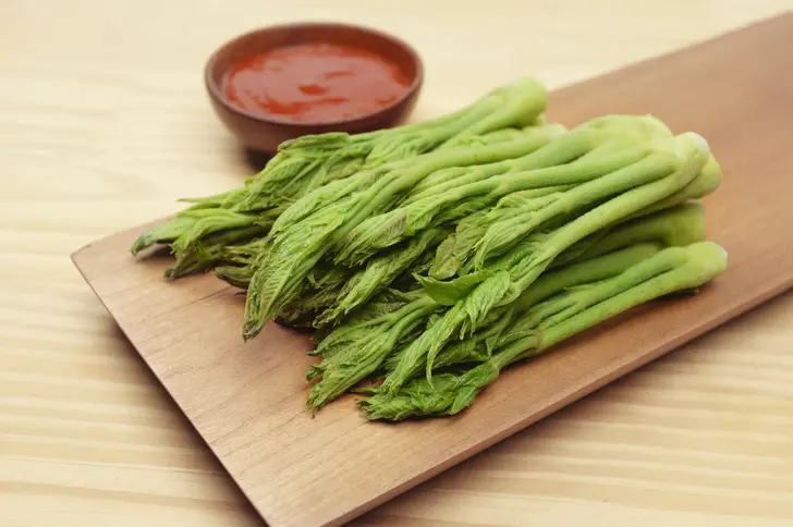 Fresh durup (Korean aralia shoots) with gochujang dipping sauce - traditional spring greens that require blanching to remove saponin toxins before eating