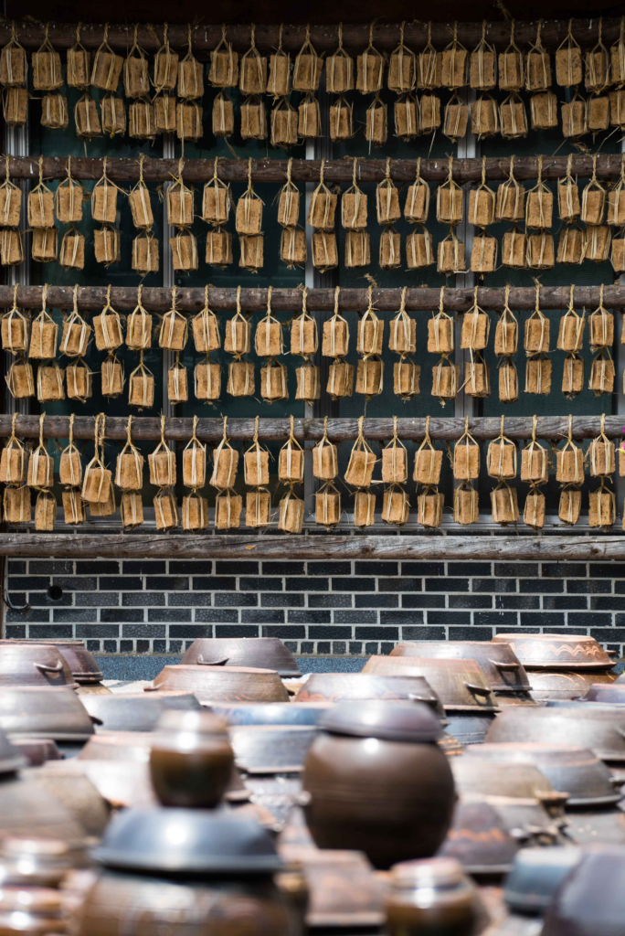 Meju soybean blocks hanging to dry above rows of onggi fermentation jars at Sunchang Traditional Gochujang Folk Village
