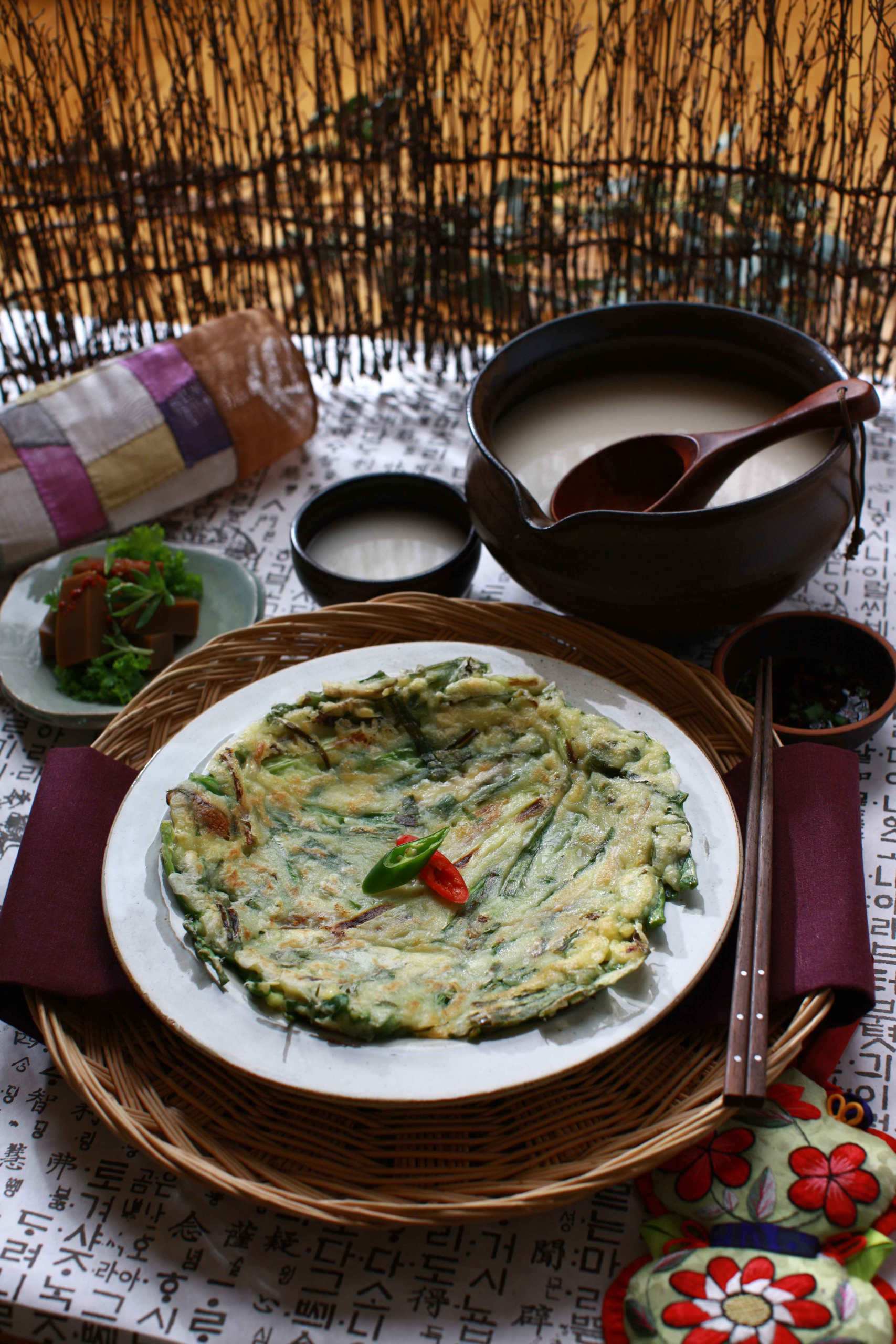 Traditional Korean table setting with pajeon (green onion pancake), makgeolli rice wine, and dotorimuk (acorn jelly) at a mountain restaurant