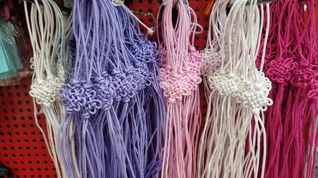 Korean silk tassels in purple, pink, and cream with maedeup knots hanging at a traditional craft shop