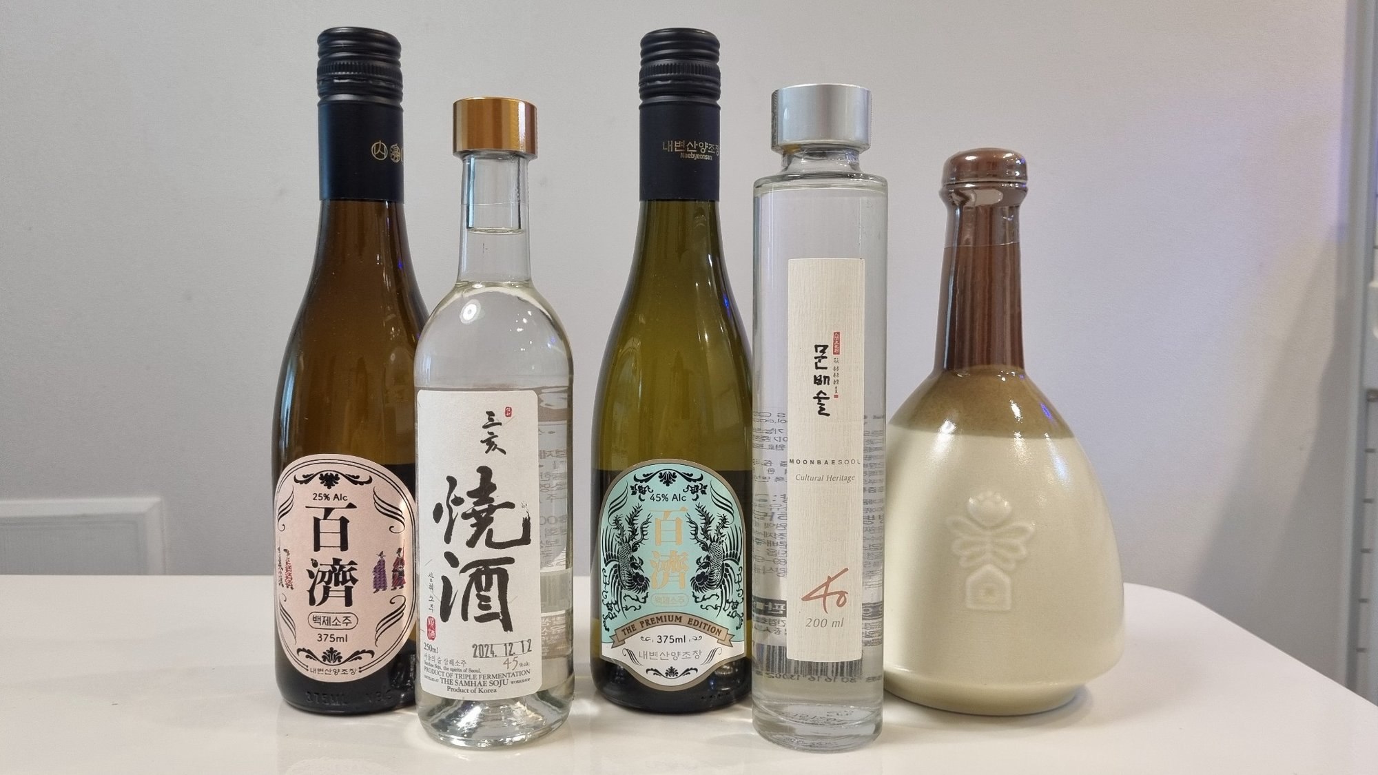 Five different Korean traditional liquors in glass and ceramic bottles side by side