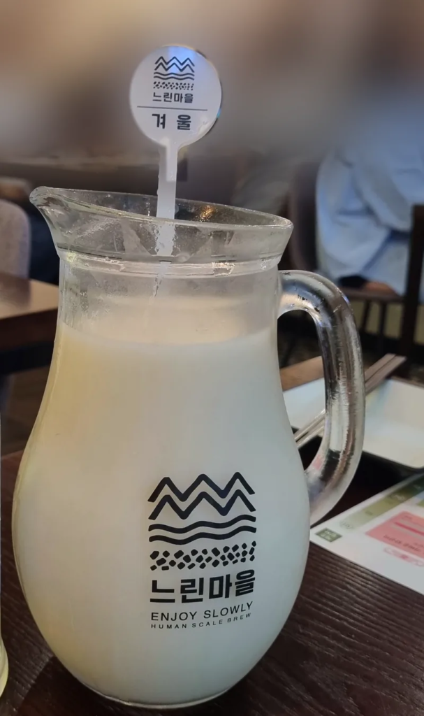 Cloudy white makgeolli served in a glass pitcher marked "winter" at a Korean brewpub 