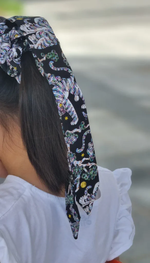 Modern Korean scrunchie with a long tail printed with minhwa folk-painting tigers, worn in a ponytail