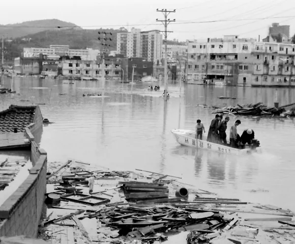 A police rescue boat crossing floodwater past collapsed houses and debris in Yeongdeungpo, Seoul, in August 1972